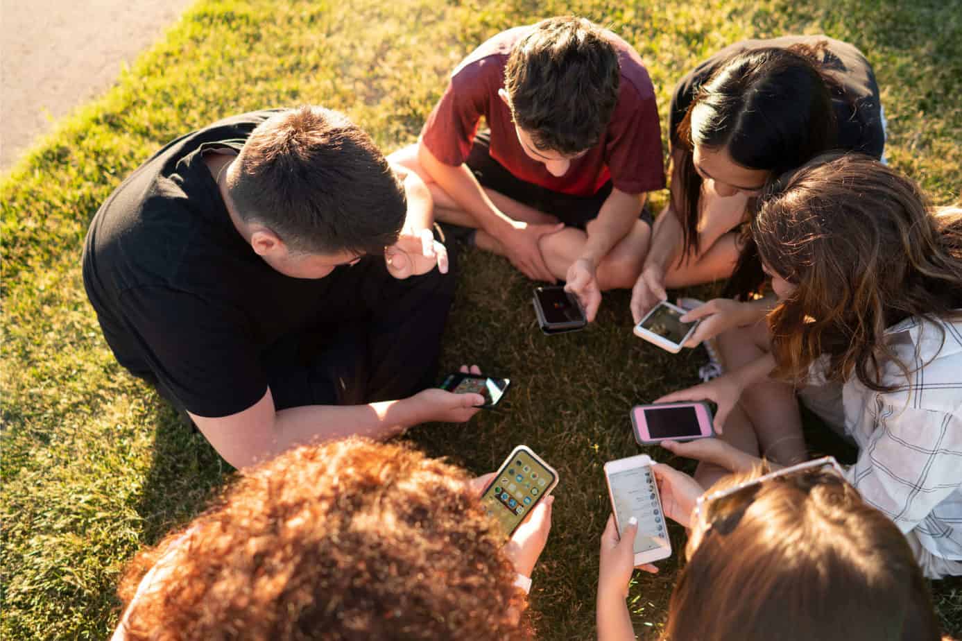 Why is TikTok so Popular - 6 teens on phones sitting in the grass